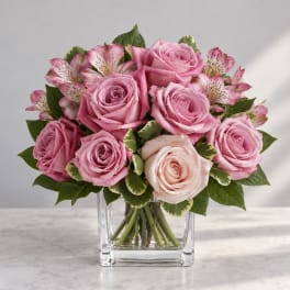 Pink roses and speckled alstroemeria in a clear glass vase