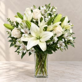 White lilies and roses arranged in a clear glass vase