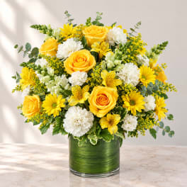 Yellow roses and white carnations in a green glass vase