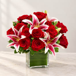 Red roses and pink lilies arranged in a square glass vase