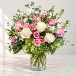 Pink and white roses with mixed blooms in a clear glass vase