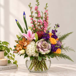 Mixed bouquet in a clear glass vase with pink, purple, orange, and white blooms