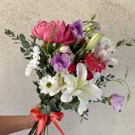 Hand-tied bouquet of pink, white, and purple flowers with a satin ribbon