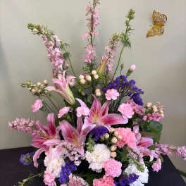 Pink lilies and carnations arranged with purple filler flowers