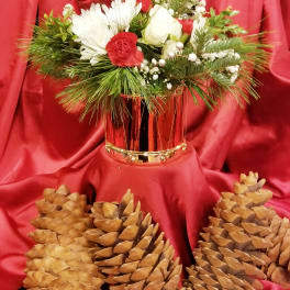 Red and white floral arrangement in a metallic vase with pinecones