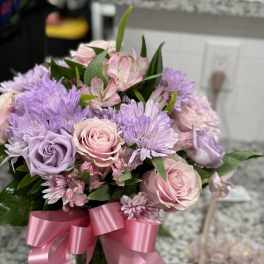 Pink and lavender bouquet with roses and daisies tied with a pink ribbon