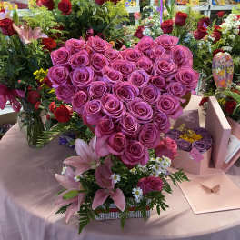 Heart-shaped bouquet of pink roses with lilies and small white daisies