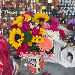 Mixed bouquet with sunflowers, roses, and daisies in a painted vase