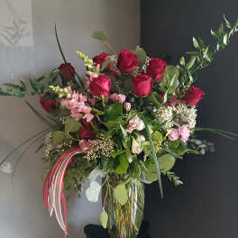 Tall bouquet of red and pink roses in a clear glass vase