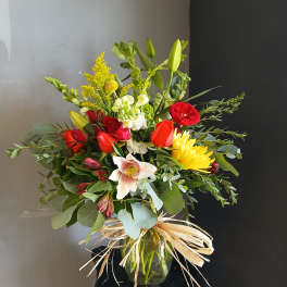 Mixed bouquet of red, yellow, and white flowers in a glass vase