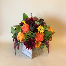 Mixed bouquet of orange and burgundy flowers in a wooden box