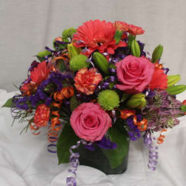 Colorful bouquet with pink roses, gerbera daisies, and lilies in a dark vase