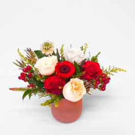 Mixed bouquet of red and cream roses in a pink vase