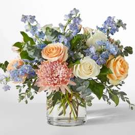 Bouquet of peach and white roses with pink blooms in a clear glass vase