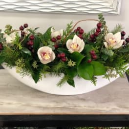 Low floral centerpiece with white orchids and red berries in a white bowl