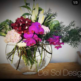 Mixed orchid arrangement in a clear glass bowl vase