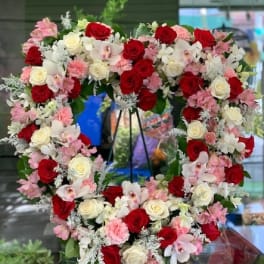 Heart-shaped floral wreath with red, white, and pink roses and orchids