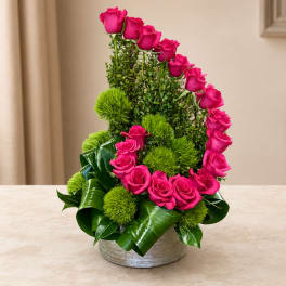 Pink roses arranged in a silver vase with bright green accents.