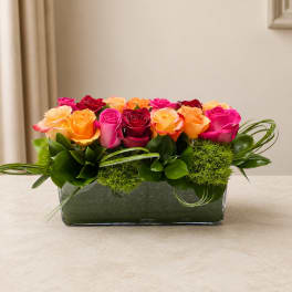 Mixed roses in a low rectangular glass vase with green accents