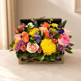 Mixed bouquet of roses, chrysanthemums, and purple blooms in a wooden box