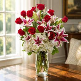 Red roses and pink lilies arranged in a clear glass vase