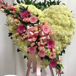 Heart-shaped floral spray with pink gerberas and roses on a stand