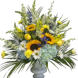 Mixed bouquet of sunflowers, hydrangeas, and daisies in a gray vase