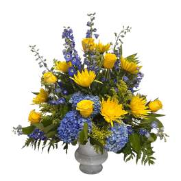 Yellow roses and blue flowers arranged in a gray vase