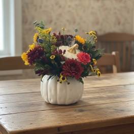 Mixed fall flowers arranged in a white pumpkin-shaped vase