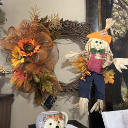 Fall wreath with sunflowers and a scarecrow decoration on a wall