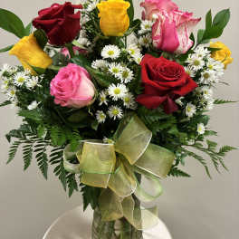 Bouquet of multicolored roses and white daisies in a glass vase