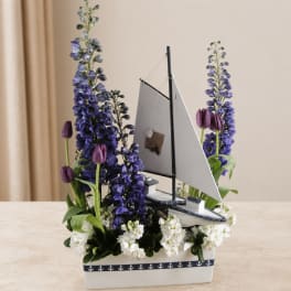 Sailboat centerpiece with purple flowers and white blooms in a white container