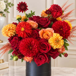 Red and orange flower arrangement in a black box