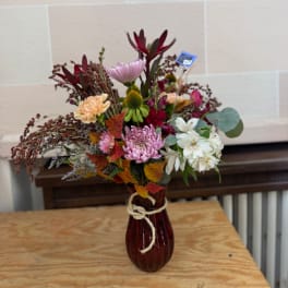 Mixed bouquet in a burgundy vase with pink, white, and red flowers