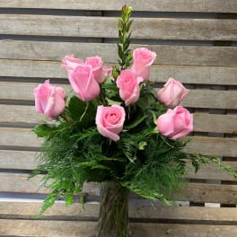 Pink roses arranged in a clear glass vase with lush greenery