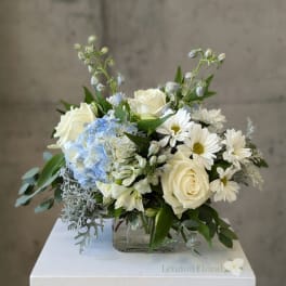White and blue floral arrangement in a clear glass vase