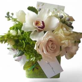 Bouquet of white orchids, roses, and green flowers in a square container