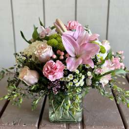 Pink lilies and roses arranged in a square glass vase