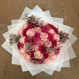 Bouquet of pink and hot pink roses wrapped in white paper