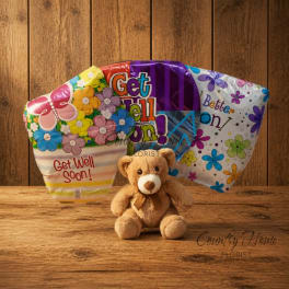 Get well balloons with a teddy bear on a wooden surface