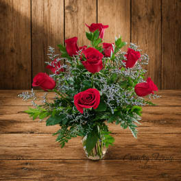 Red roses arranged in a clear glass vase with airy filler