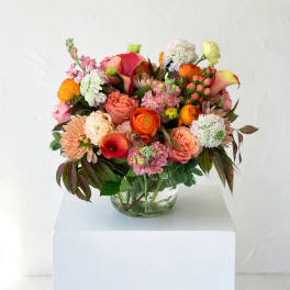 Mixed bouquet in a clear glass vase with pink, orange, and white blooms