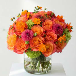 Orange and pink flower bouquet in a clear glass vase
