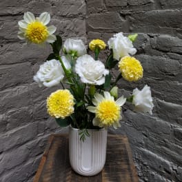 White and yellow flowers arranged in a ribbed white vase
