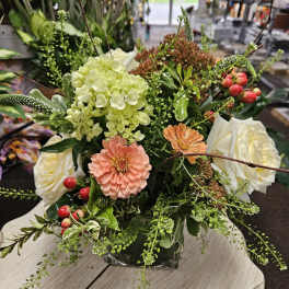 Low mixed arrangement with peach blooms, white roses, hydrangea, and berries in a square glass vase