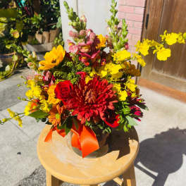 Bright mixed bouquet in a glass vase with red, yellow, and orange flowers