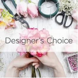 Hands arranging pink flowers with floral tools on a white table