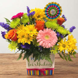 Colorful birthday flower arrangement in a decorated square container