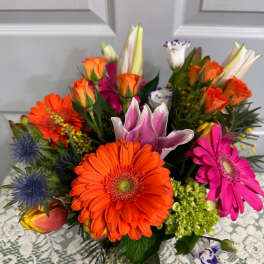 Bright mixed bouquet with orange gerberas, roses, lilies, and pink blooms