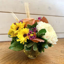 Yellow daisies and white chrysanthemum in a glass vase with peach rose accents